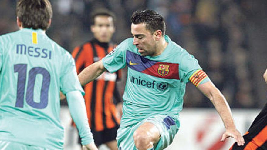 Xavi supera a Mkhitaryan apoyado por Messi.