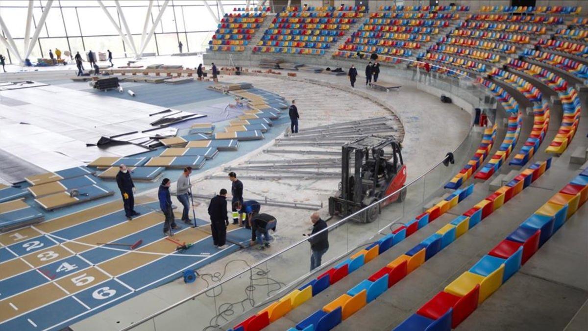 Varios operarios trabajan desmontando la pista cubierta de atletismo de Sabadell para montar un hospital de campaña