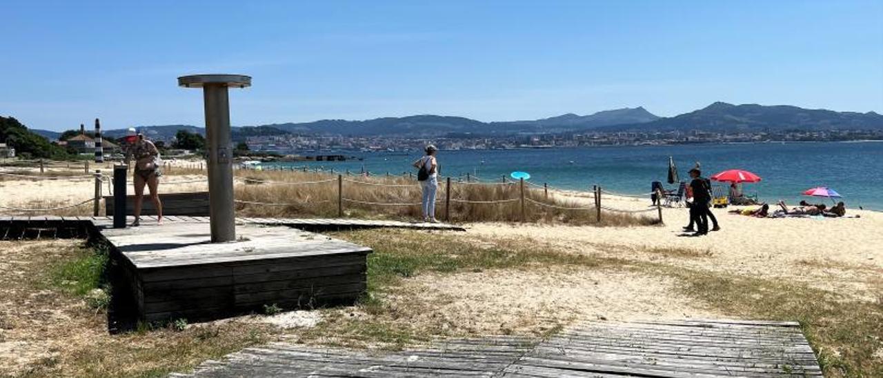 Usuarios de la playa de Rodeira, acudiendo al servicio de duchas y lavapiés instalados en el arenal. | // G.NÚÑEZ