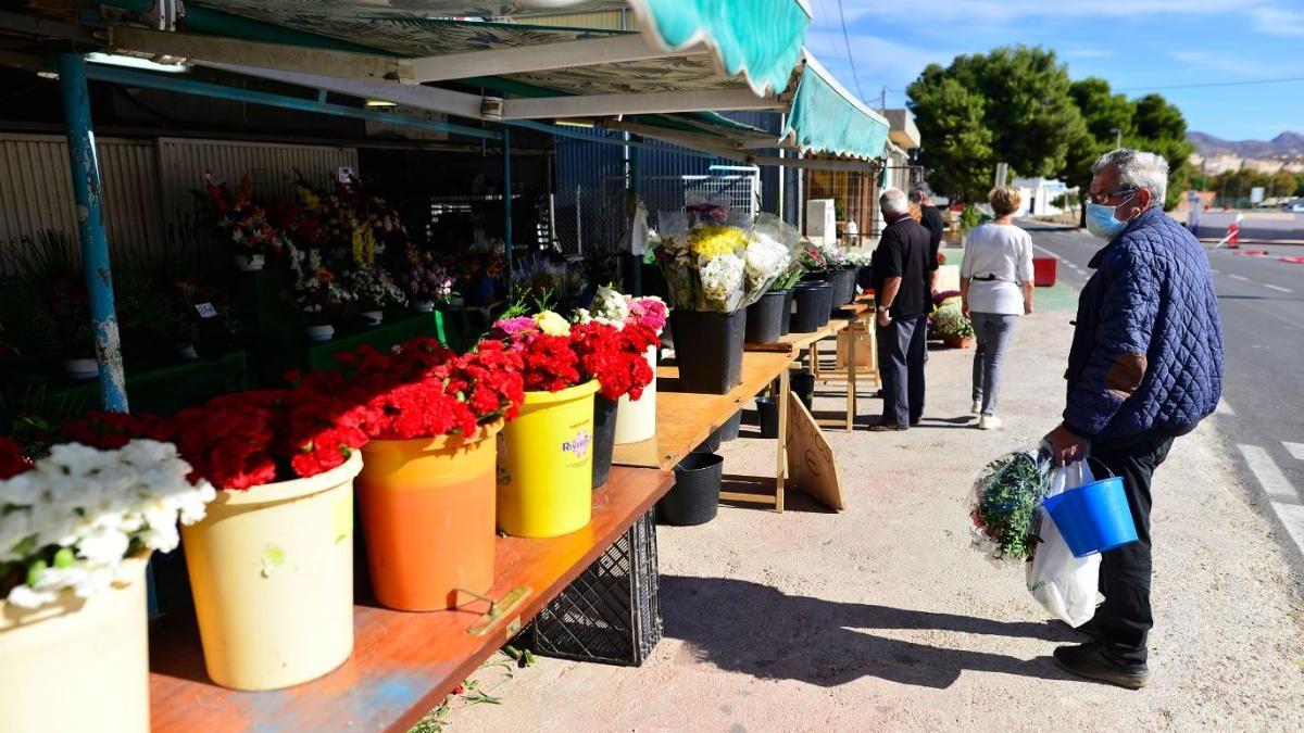 Un señor mira flores en un puesto en el cementerio de San Antón, en Cartagena.