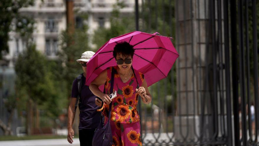 Una mujer pasea protegiéndose del sol con un paraguas, el martes en Madrid.