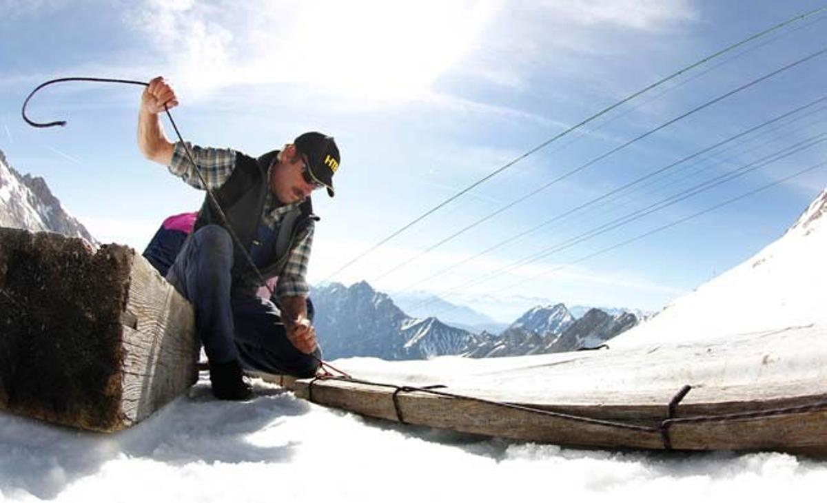 Un treballador fa tasques de manteniment d’un telecadira sobre el gel del cim del Zugspitze, la muntanya més alta d’Alemanya (2.962 metres).
