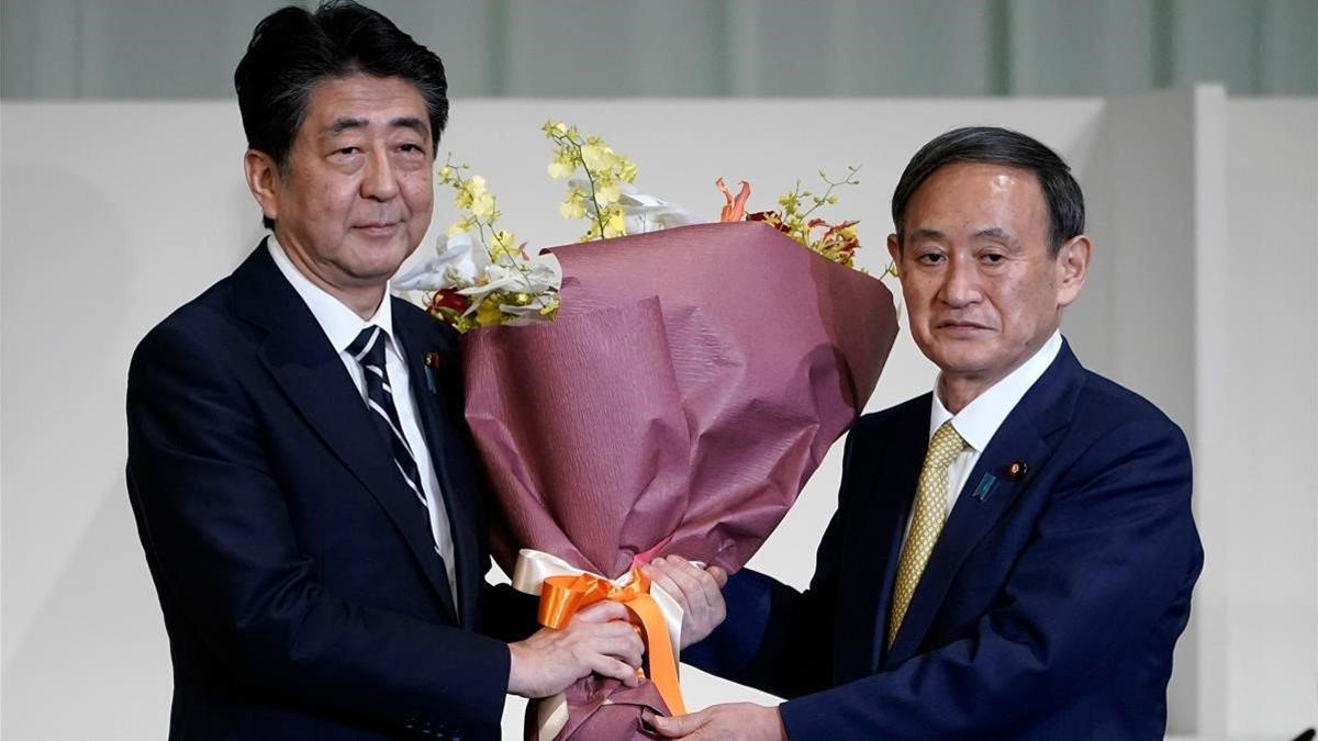 Suga (derecha) recibe un ramo de flores tras convertirse en el lider del partido gubernamental de Japón.