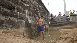 El aumento de arena en la playa de San Lorenzo de Gijón obliga a cavar una zanja para ducharse