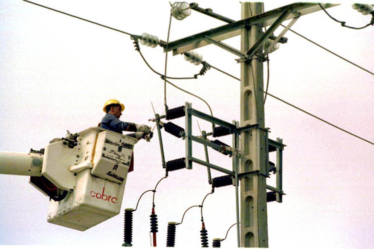 Un equip tècnic repara un pal d’electricitat.