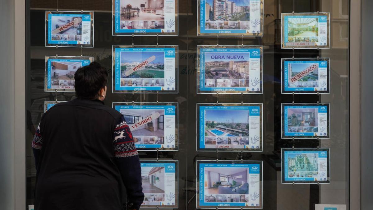 Una persona mira los carteles de vivienda de una agencia inmobiliaria.