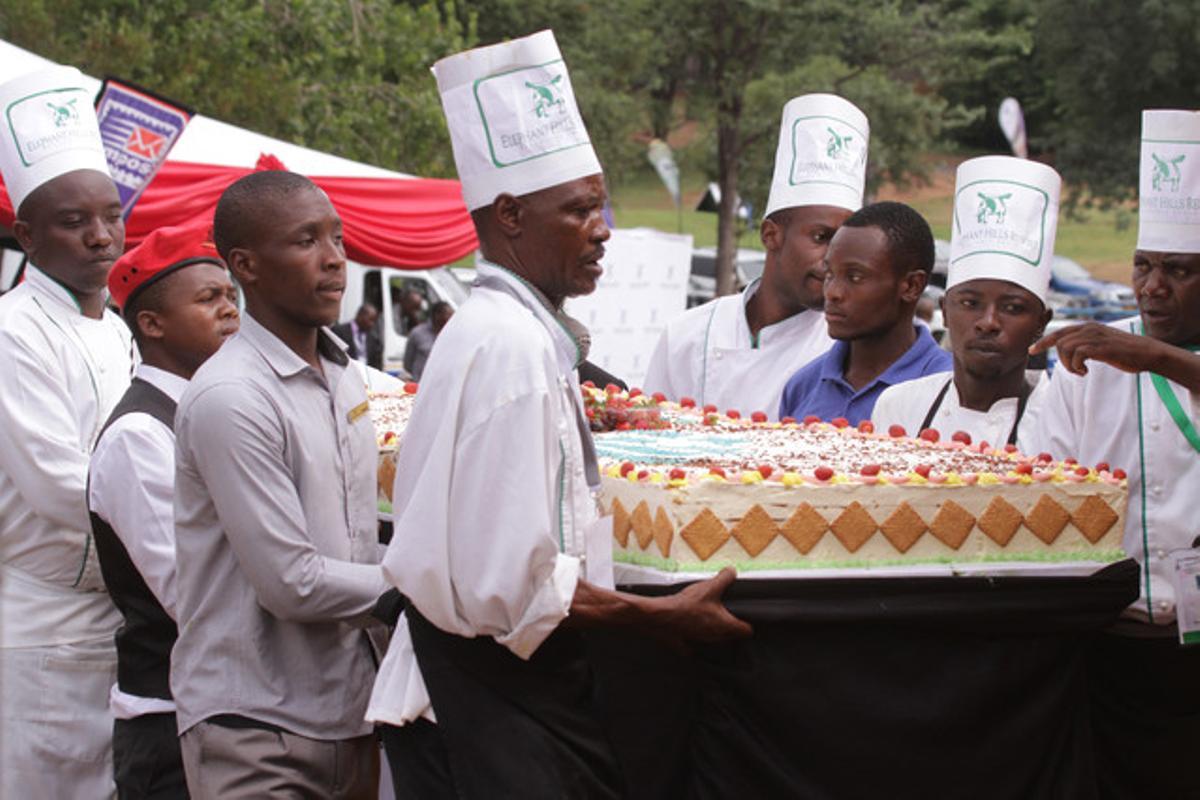 Els cuiners porten un dels vuit pastissos amb què s’ha celebrat l’aniversari de Mugabe.