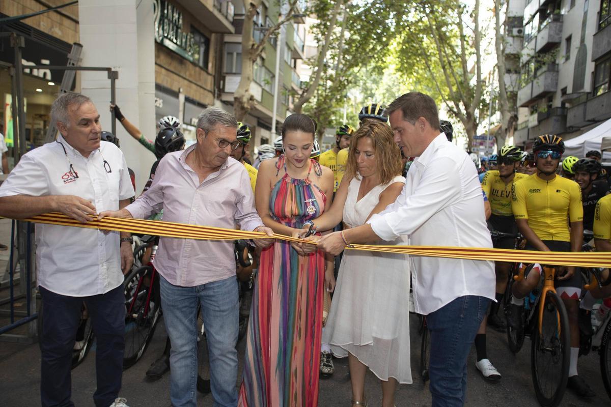 La delegada del gobierno, Pilar Bernabé, corta la cinta del Trofeu de Ciclisme de la Fira junto al alcalde, la Reina de la Fira, el regidor de Deportes y el responsable de la organización de la prueba