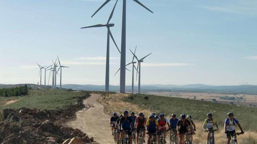 Ciclistas pasan junto a un parque eólico.