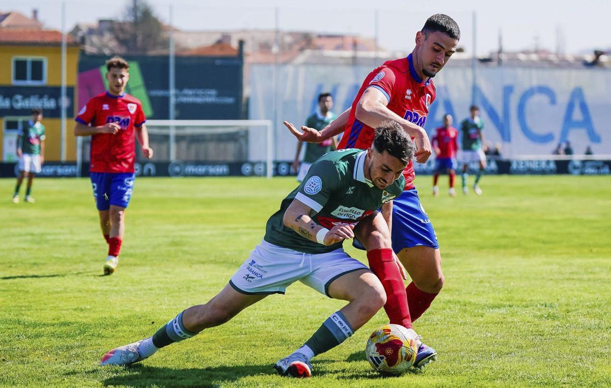 Nacho Fariña lucha con un jugador del Numancia por controlar un balón. | PEDRO MINA