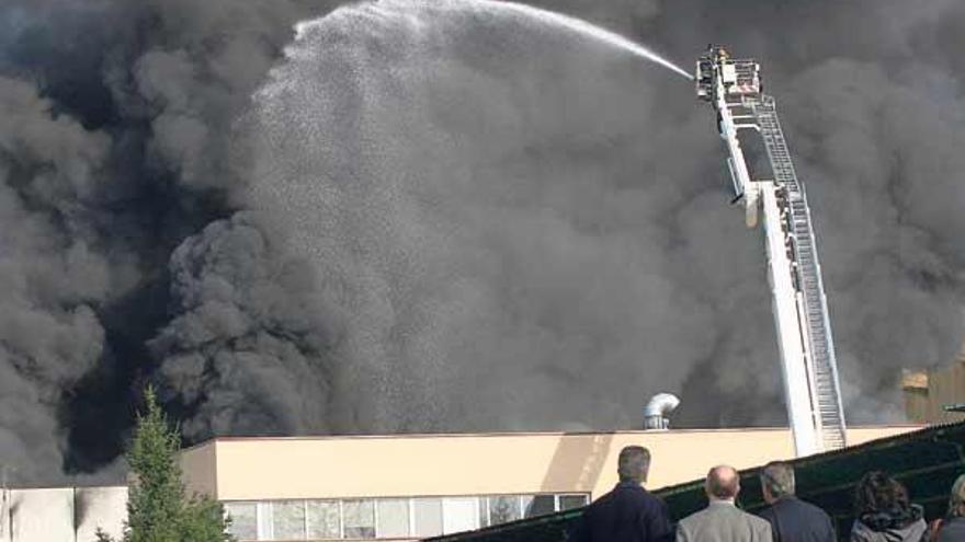 Directivos y trabajadores de la empresa observaron cómo los bomberos trataban de controlar las llamas y la densa columna de humo negro.