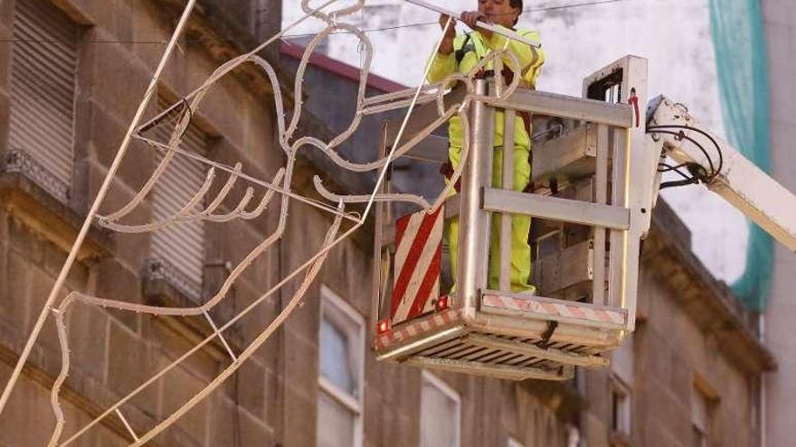 Un operario coloca las luces de Navidad en Sanjurjo Badía. // R. Grobas