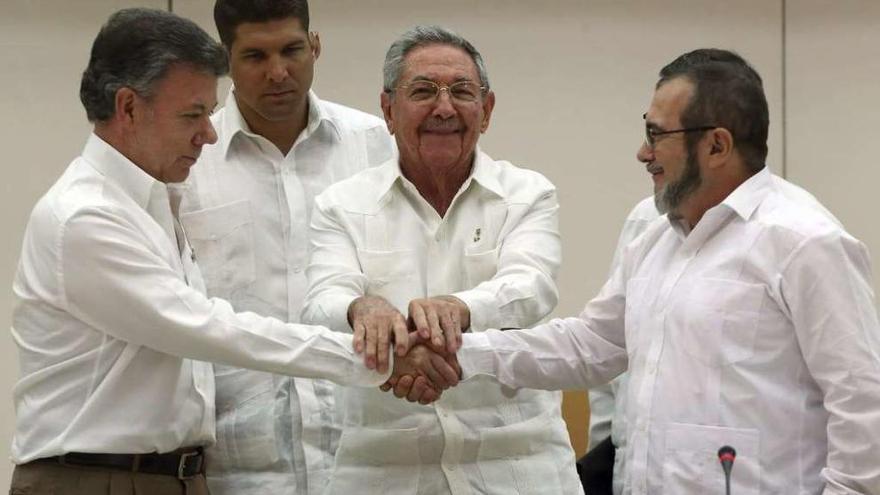 Raúl Castro (centro) aprieta las manos de Juan Manuel Santos (izda.) y &quot;Timochenko&quot; (dcha.). // Efe