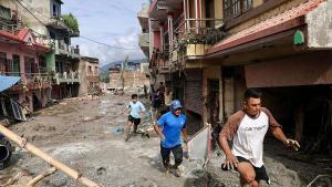 TOPSHOT - Local residents walk past houses lying deluged in sludge after flash floods at Devighat, Bidur Municipality in Nepals Nuwakot district on August 27, 2026. Nepals disaster agency said that 823 people remained out of contact on August 27, more than 24 hours after a deadly flood tore through the border region with Tibet. (Photo by Prabin RANABHAT / AFP)