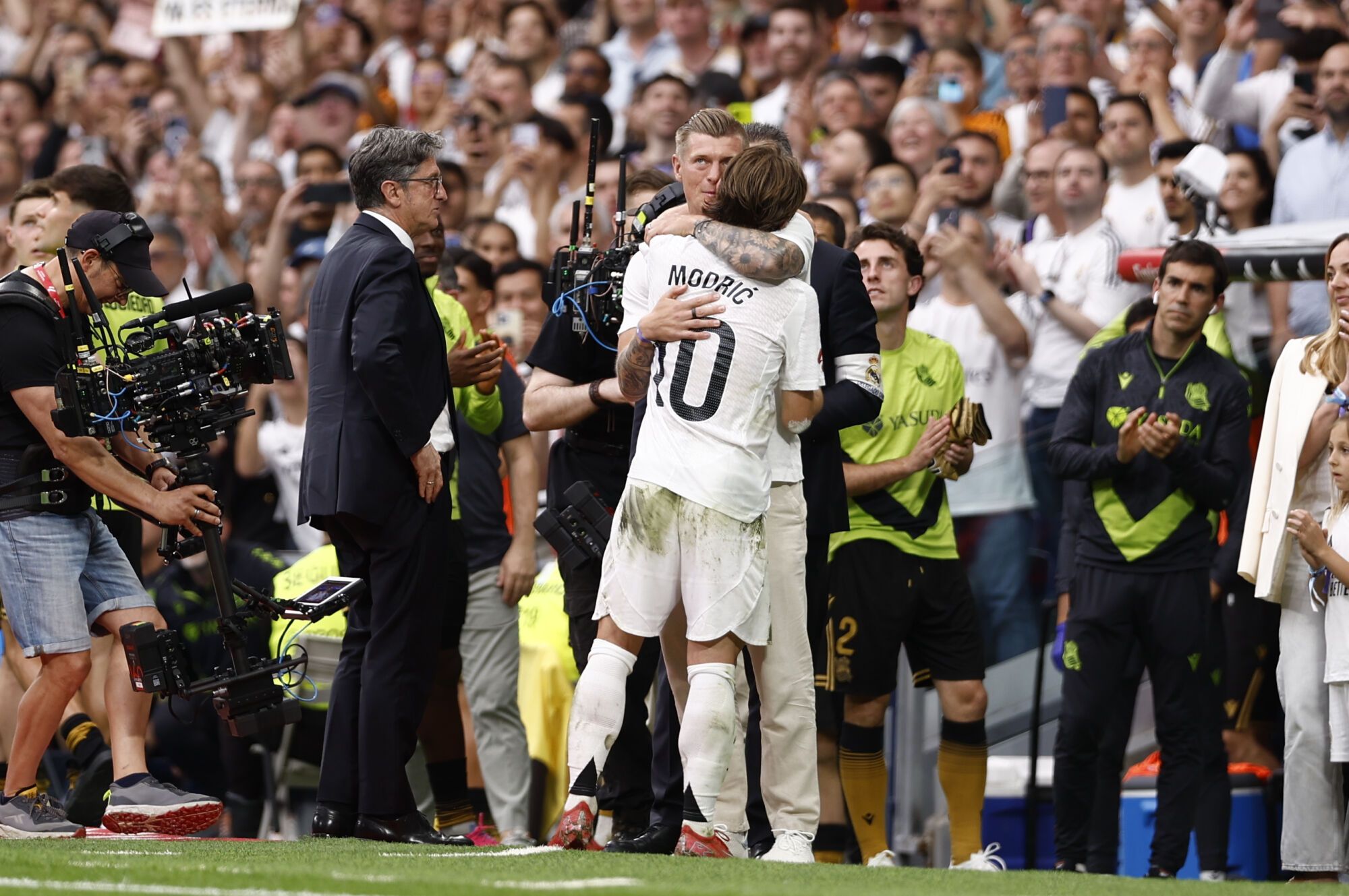 MADRID, 24/05/2025.- El centrocampista croata del Real Madrid Luka Modrić (c-d) se abraza con el ex jugador Toni Kroos tras ser sustituido en su último partido en el Santiago Bernabéu durante el partido de la jornada 38 de LaLiga EA Sports entre Real Madrid y Real Sociedad celebrado este sábado en el estadio Santiago Bernabéu de Madrid. EFE/ Daniel González