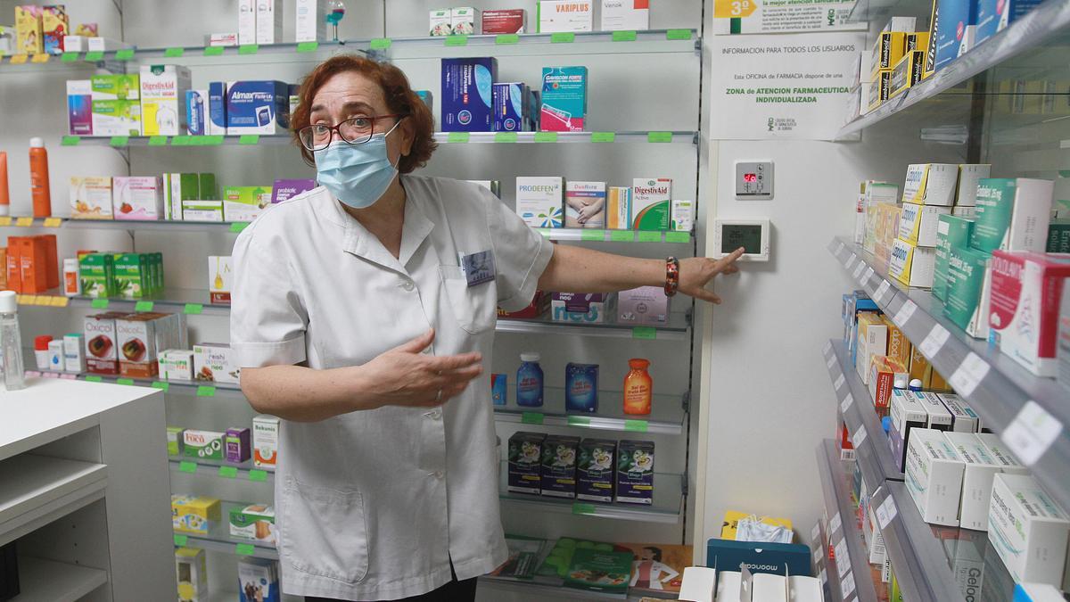 Rosa Gayo muestra el termostato que marcha 26,5º en la farmacia, sin aire acondicionado.