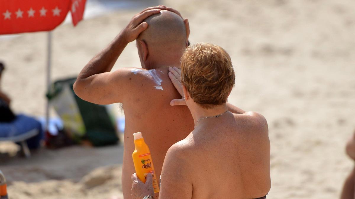 Una mujer le pone crema solar a un hombre en una playa de Sanxenxo (Pontevedra).