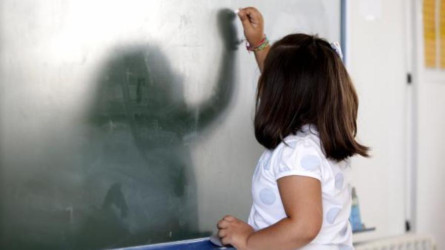 Una alumna de Primaria escribe en la pizarra.