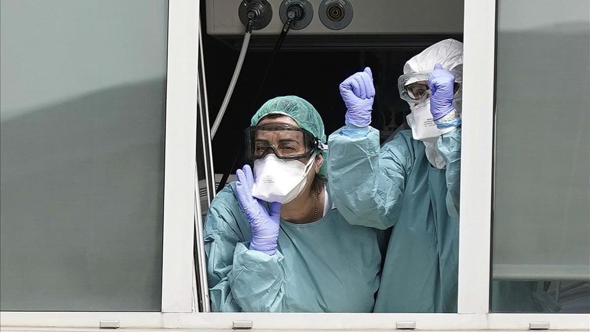 Dos sanitarios del madrileño Hospital de La Paz saludan al público que les anima desde el exterior.