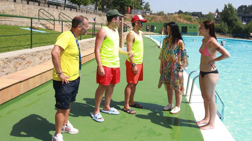 Un par de socorristas explicando las normativas de la piscina este fin de semana en Oira.