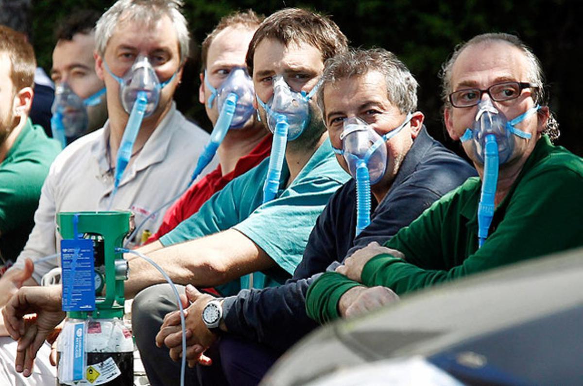 Un grup de treballadors inhalen oxigen a través d’una mascareta després de ser evacuats de l’empresa d’amortidors Kybse a causa d’un incendi, en què dos treballadors han resultat ferits lleus, a Ororbia (Navarra).