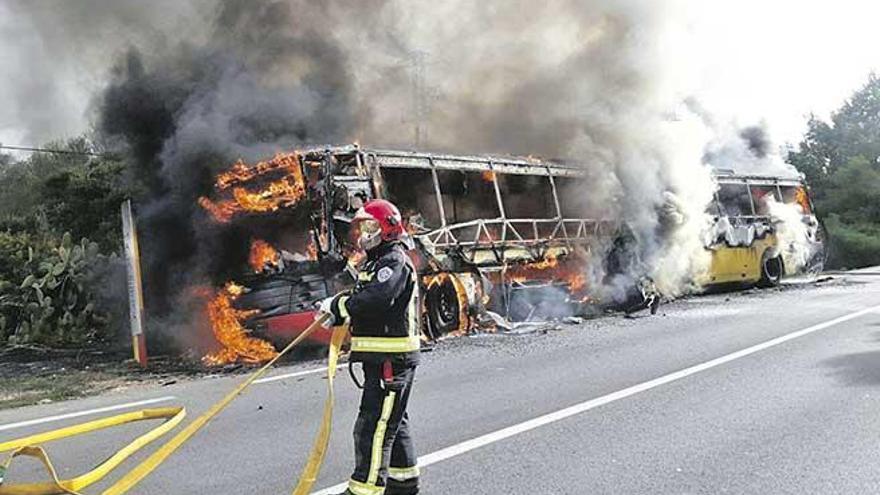 Un bombero, frente al autobús envuelto en llamas ayer al mediodía a las afueras de Campos.