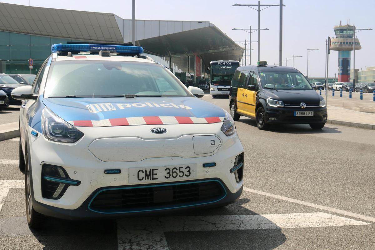 Un coche patrulla de Mossos en el aeropuerto de Barcelona junto a un taxi