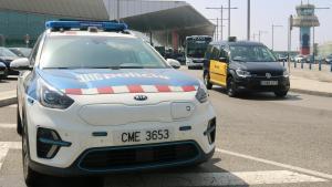 Un coche patrulla de Mossos en el aeropuerto de Barcelona junto a un taxi