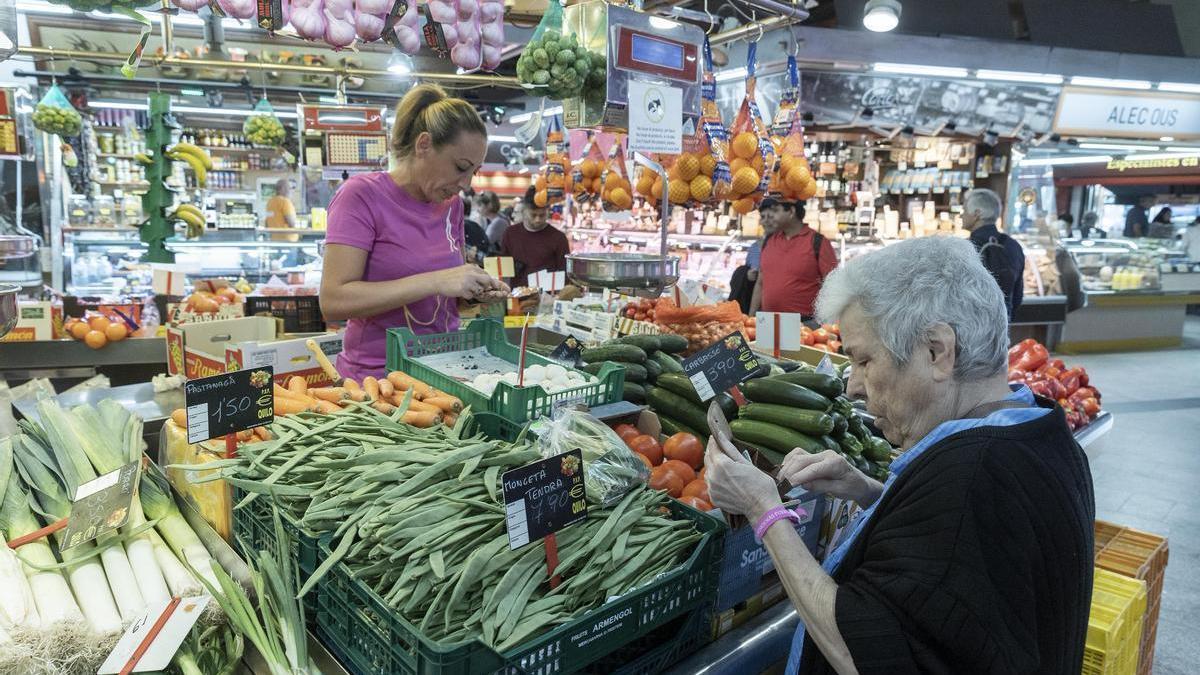 Varias personas comprando en un frutería.