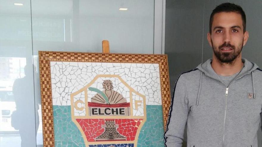 Isidoro, delante de un escudo del Elche CF