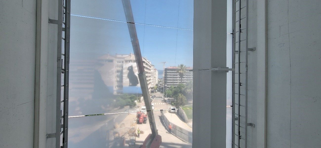 Vista interior desde el ascensor, con la grúa y los edificios al fondo