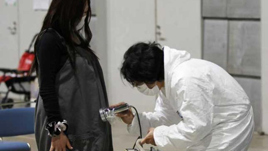 Un técnico realiza un test de radiactividad a una mujer embarazada en Fukushima.