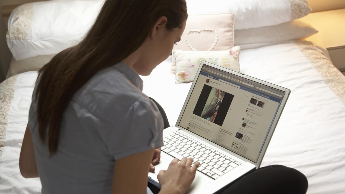 Una joven se conecta a su perfil de Facebook desde su ordenador portátil. / El Correo