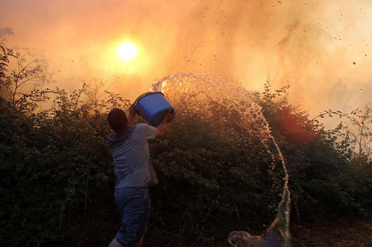 Un noi intenta sufocar les flames de l’incendi a la localitat lleonesa de Molinaseca, després del foc que s’ha originat en una nau i s’ha estès a les cases.