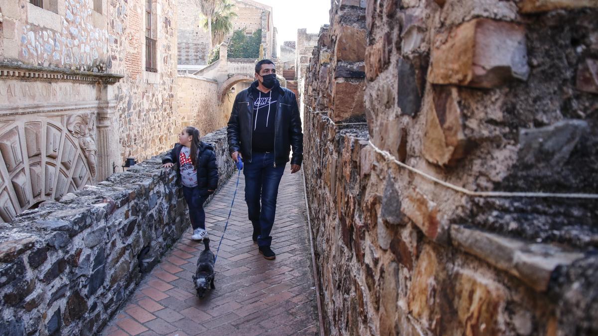 Dos turistas pasean por la muralla de Cáceres.