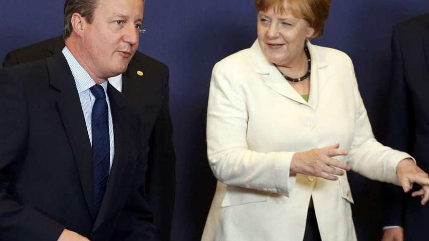 Merkel orienta a un Cameron dubitativo sobre el lugar que debe ocupar en la foto de familia. // Reuters