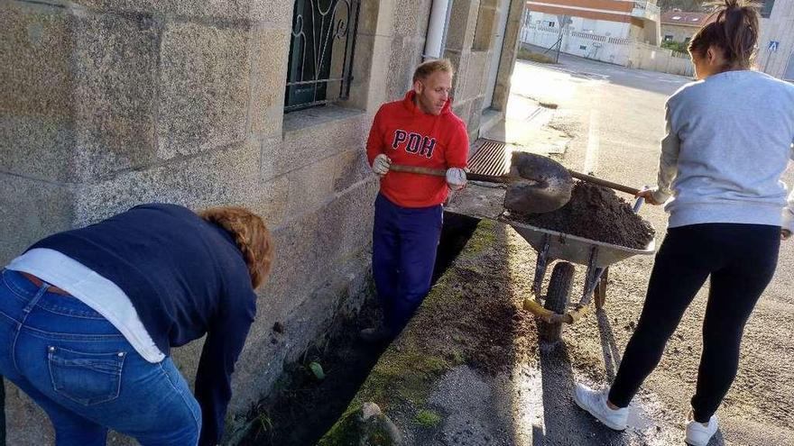 Martín Otero y otras dos vecinas retiran tierra y vegetación de una cuneta en Ponte Nova. // Castro e Ladeira