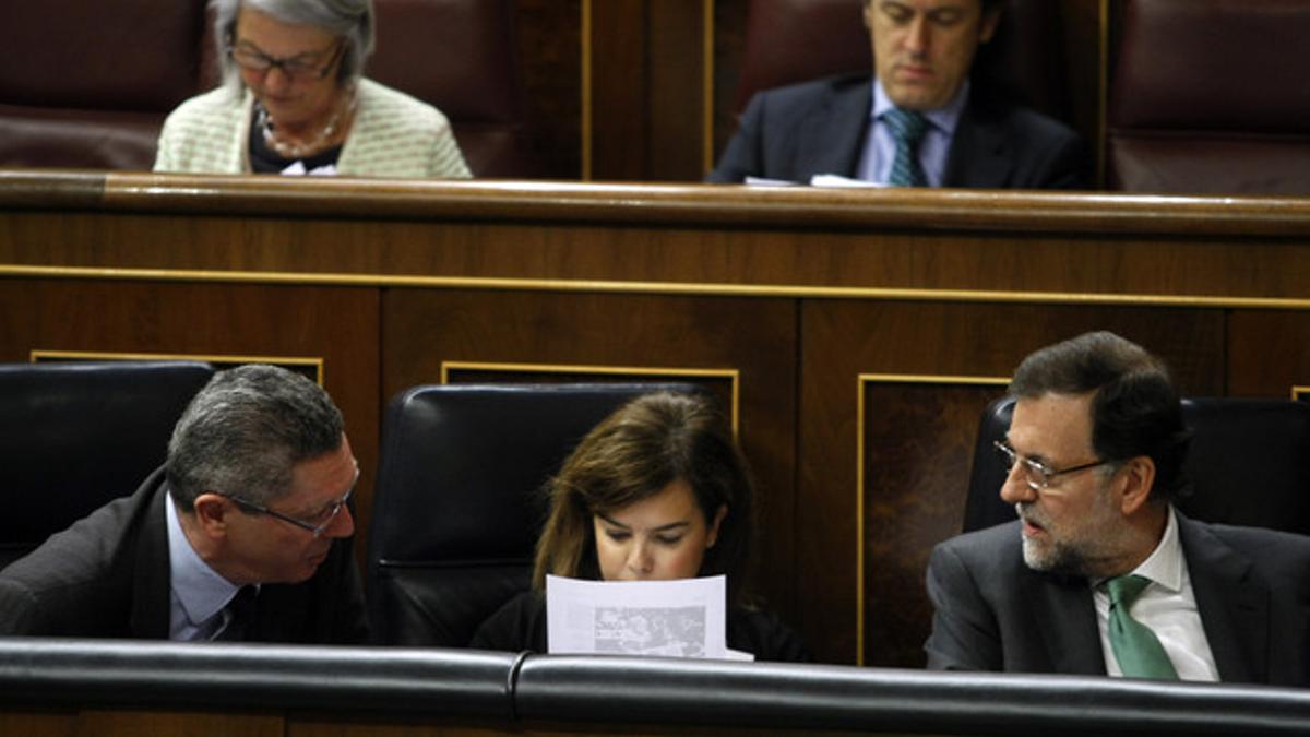 Gallardón (izquierda) conversa con Rajoy ante Soraya Sáenz de Santamaría, en el Congreso.
