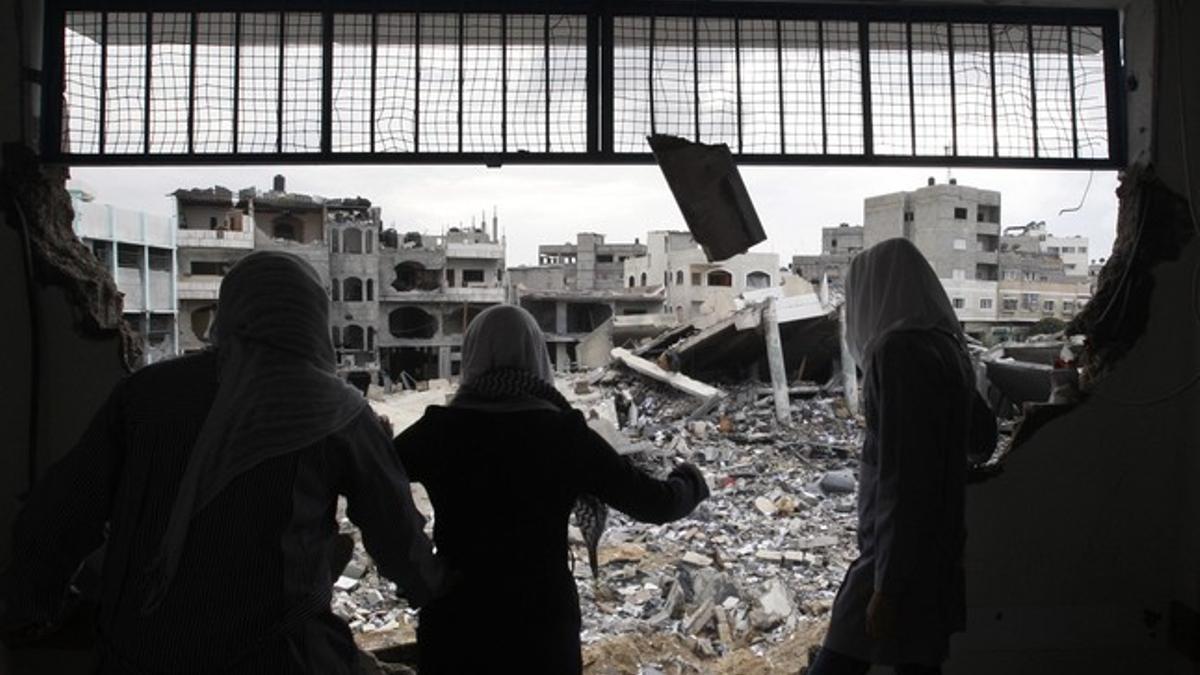 Unas jóvenes estudiantes palestinas miran los edificios destruidos desde su escuela, este sábado.