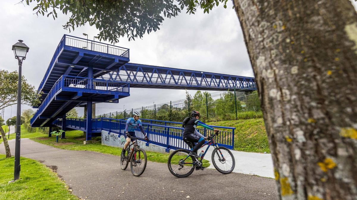 Dos ciclistas pasan por delante de una de las dos máquinas que quedan en pie.