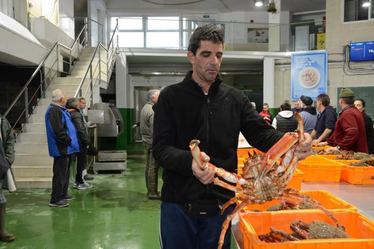 Un marinero muestra un ejemplar de centolla, ayer en la lonja de Bueu. | // G.NÚÑEZ