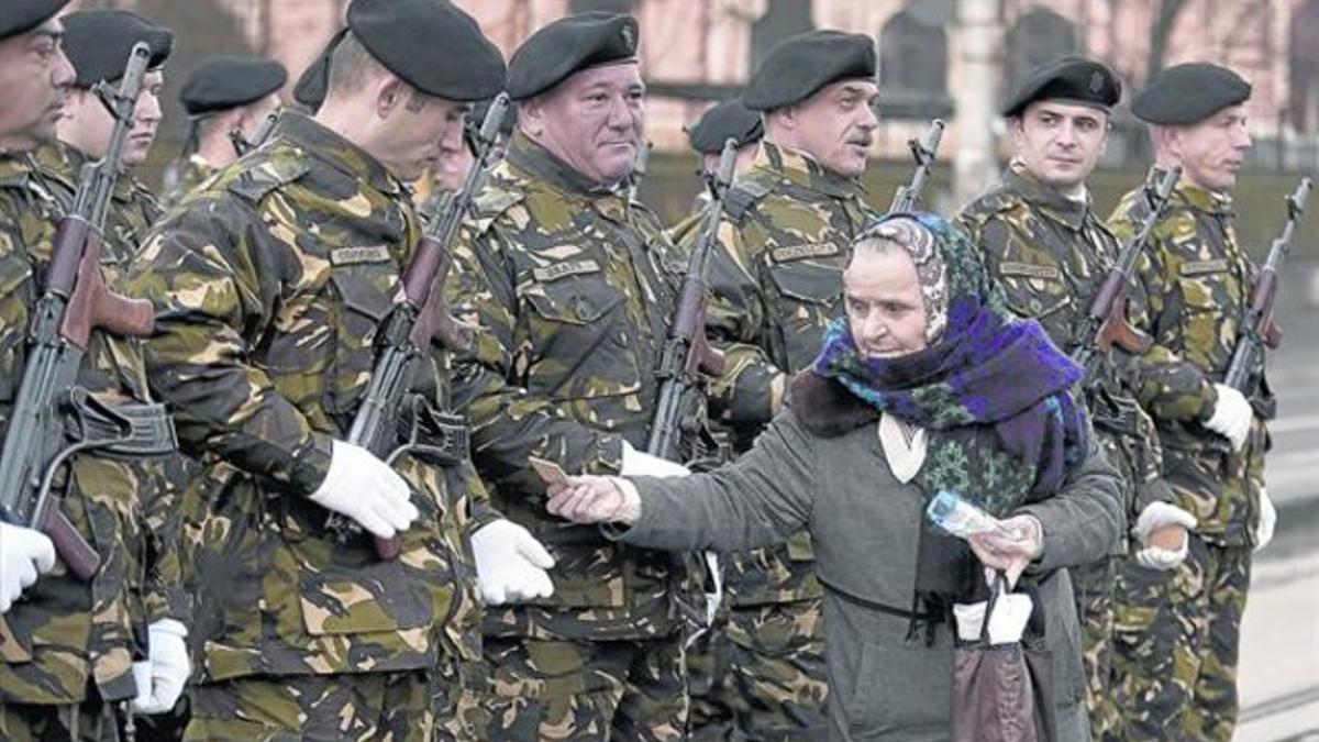 Una mujer ofrece galletas a los soldados de guardia rumanos que participan en los actos conmemorativos de la revolución, esta semana en Bucarest.