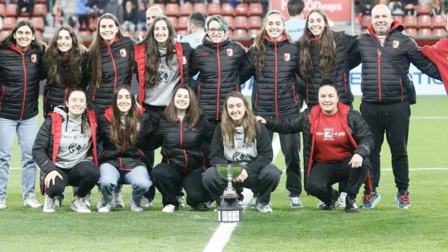 Arriba, jugadoras, técnicos y auxiliares del Telecable Gijón, posando con la Copa Intercontinental, ayer, en El Molinón. A la izquierda, Sara Roces, una de las componentes de la plantilla campeona, realiza el saque de honor. | Marcos León