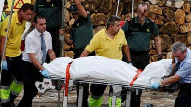Efectivos de emergencias y de los servicios funerarios, trasladando a una de las víctimas.