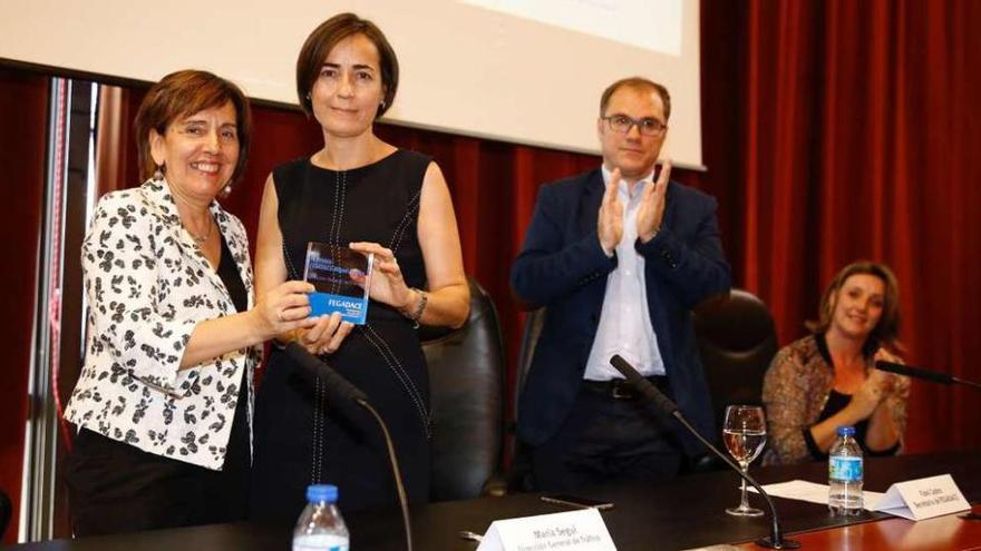 La directora de Acción Social de la Fundación Barrié, a la izquierda, entrega el premio a María Seguí.