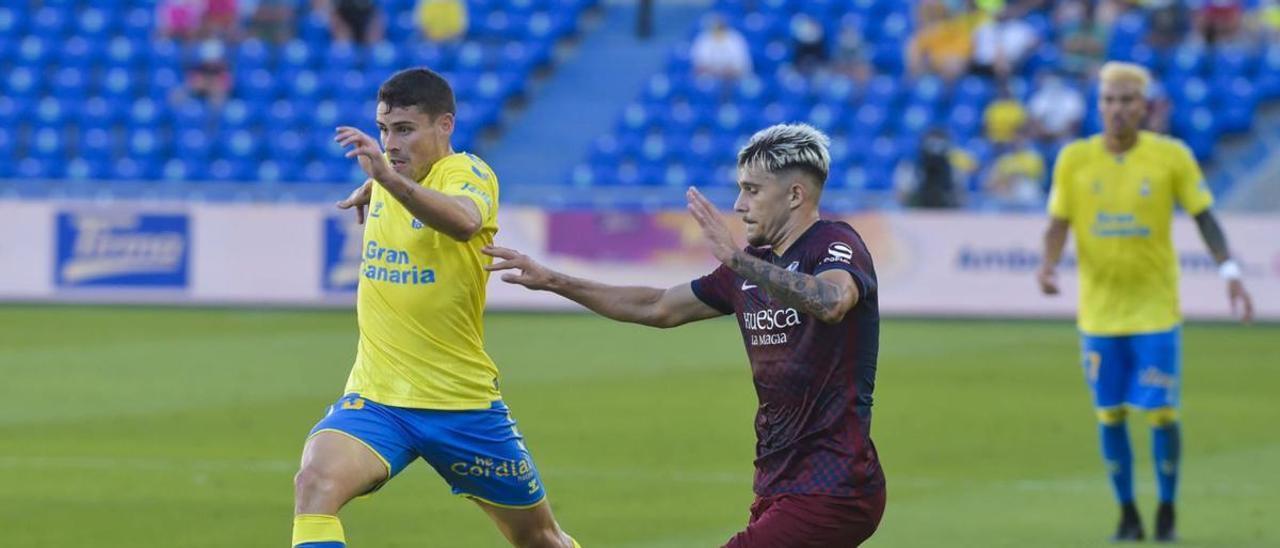 Sergio Ruiz conduce el balón perseguido por un jugador del Huesca, con Peñaranda al fondo, en la tercera jornada del campeonato pasado. | | ANDRÉS CRUZ