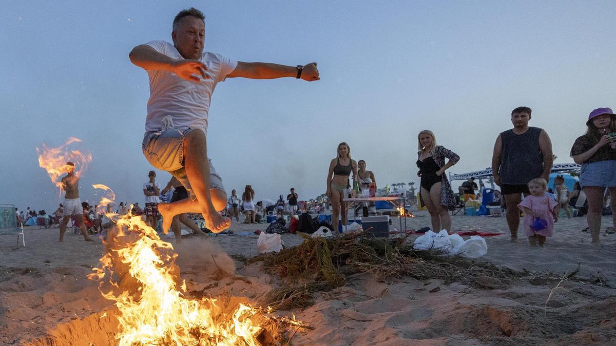 Un hombre salta la hoguera en la playa de Castelló.