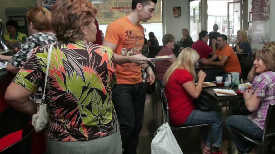 De izquierda a derecha, clientes en la cafetería, situada en la zona de la plaza de Madrid,         el pasado viernes; el propietario del establecimiento, Antonio Navarro; y la máquina en la que los clientes obtienen su número para poder pedir su café y su tostada.