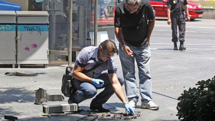 Agentes examinan los efectos causados por la detonación, que destruyó la papelera.