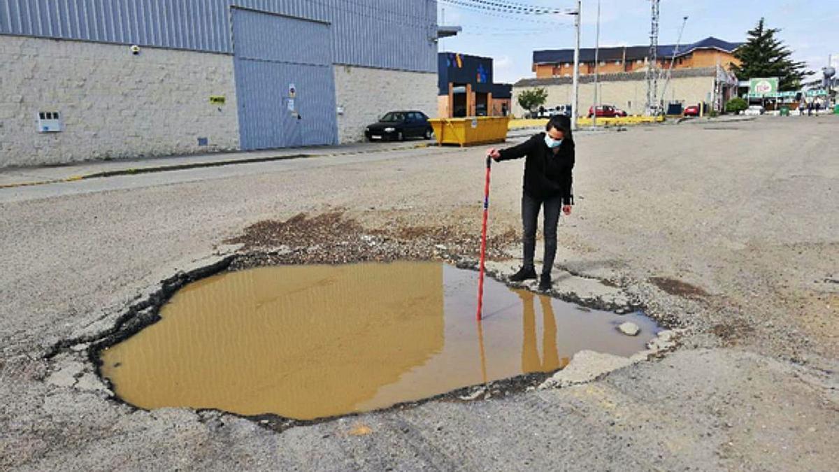 La hostelera Pilar González muestra la profundidad de uno de los enormes baches al que llaman “el cráter”. | M. F.